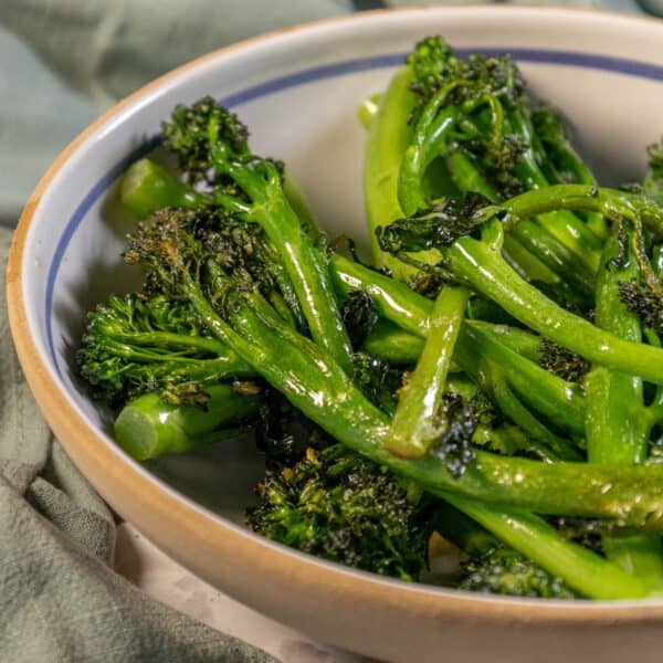 A bowl of broccolini in a white bowl.