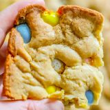 A person showcasing a gooey Easter blondies recipe with Cadbury eggs and m&m's.