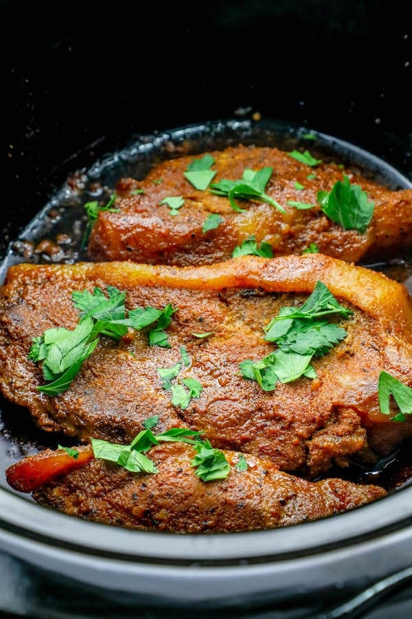 picture of pork steaks in slow cooker with parsley on top