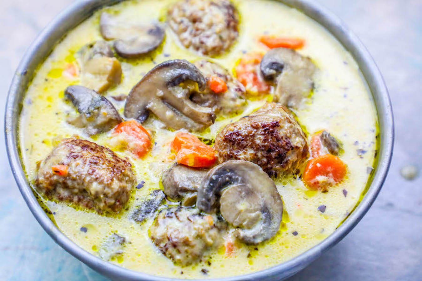 meatballs in a creamy soup with carrot and mushrooms