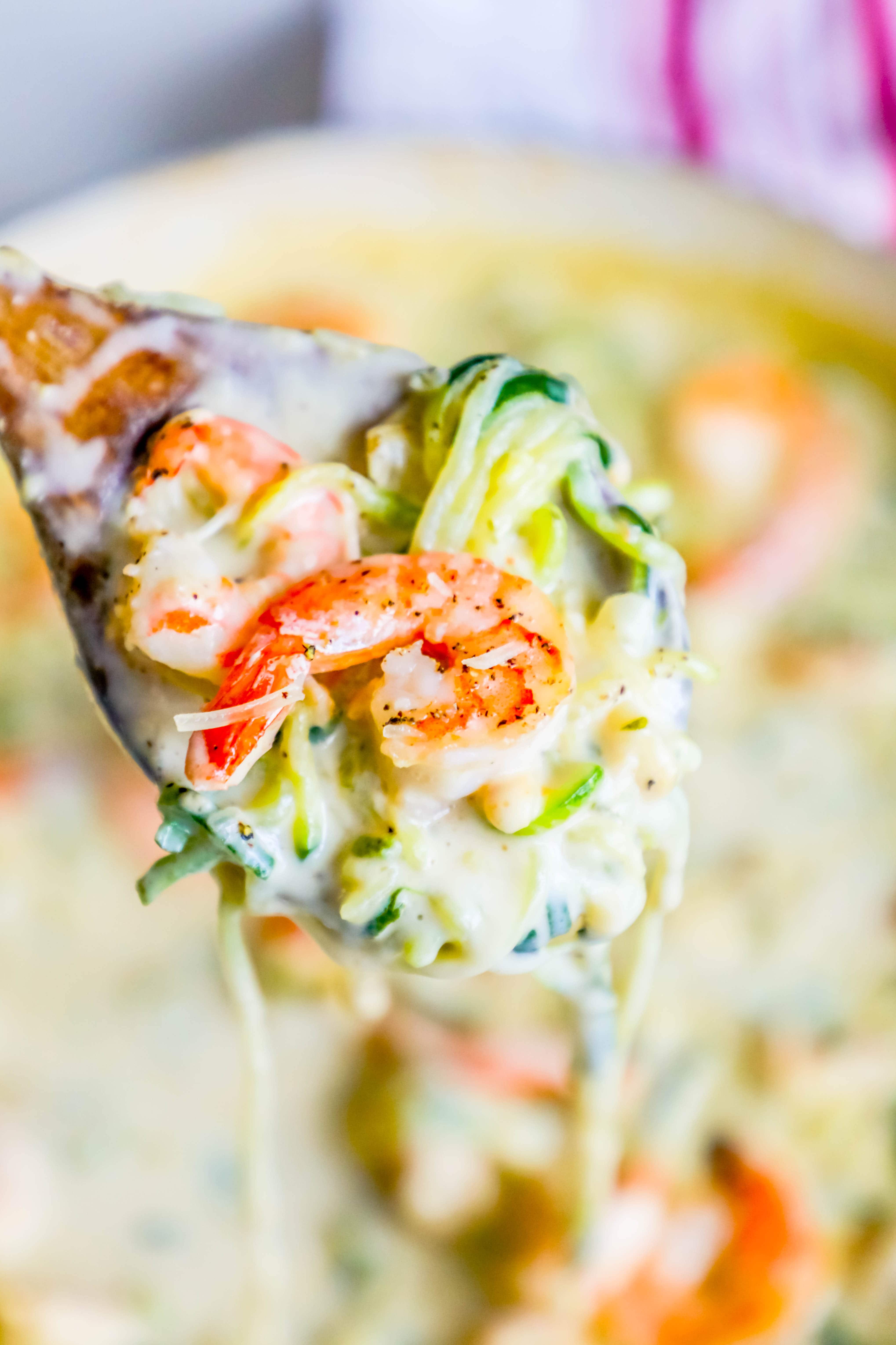 shrimp in a creamy sauce with noodles made out of zucchini on a spoon