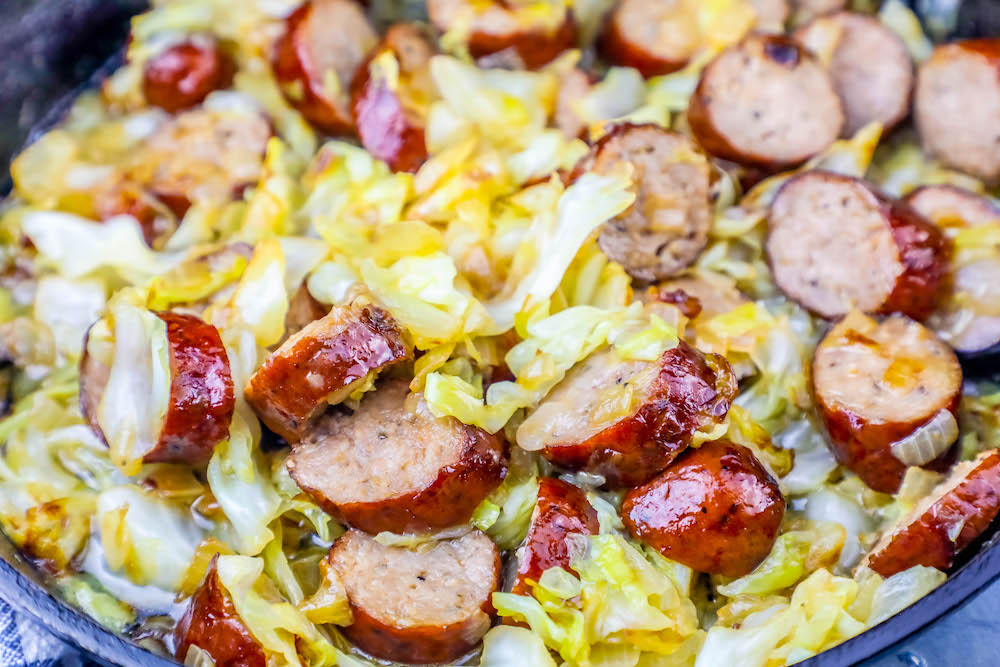 picture of sausage, onions, and cabbage sautéed in a pan 