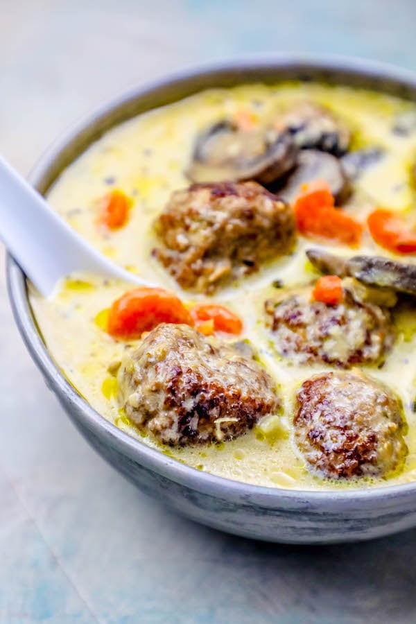 meatballs in a creamy soup with carrot and mushrooms