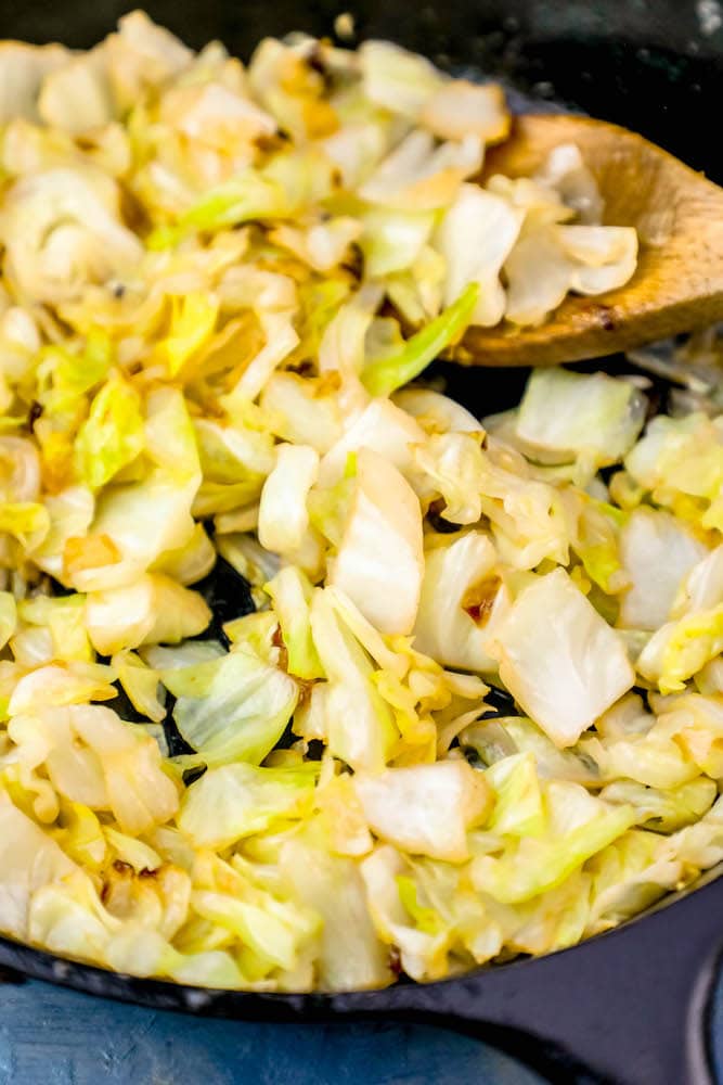 sautéed cabbage in a cast iron pan with a wooden spoon