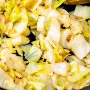 sautéed cabbage in a cast iron pan with a wooden spoon