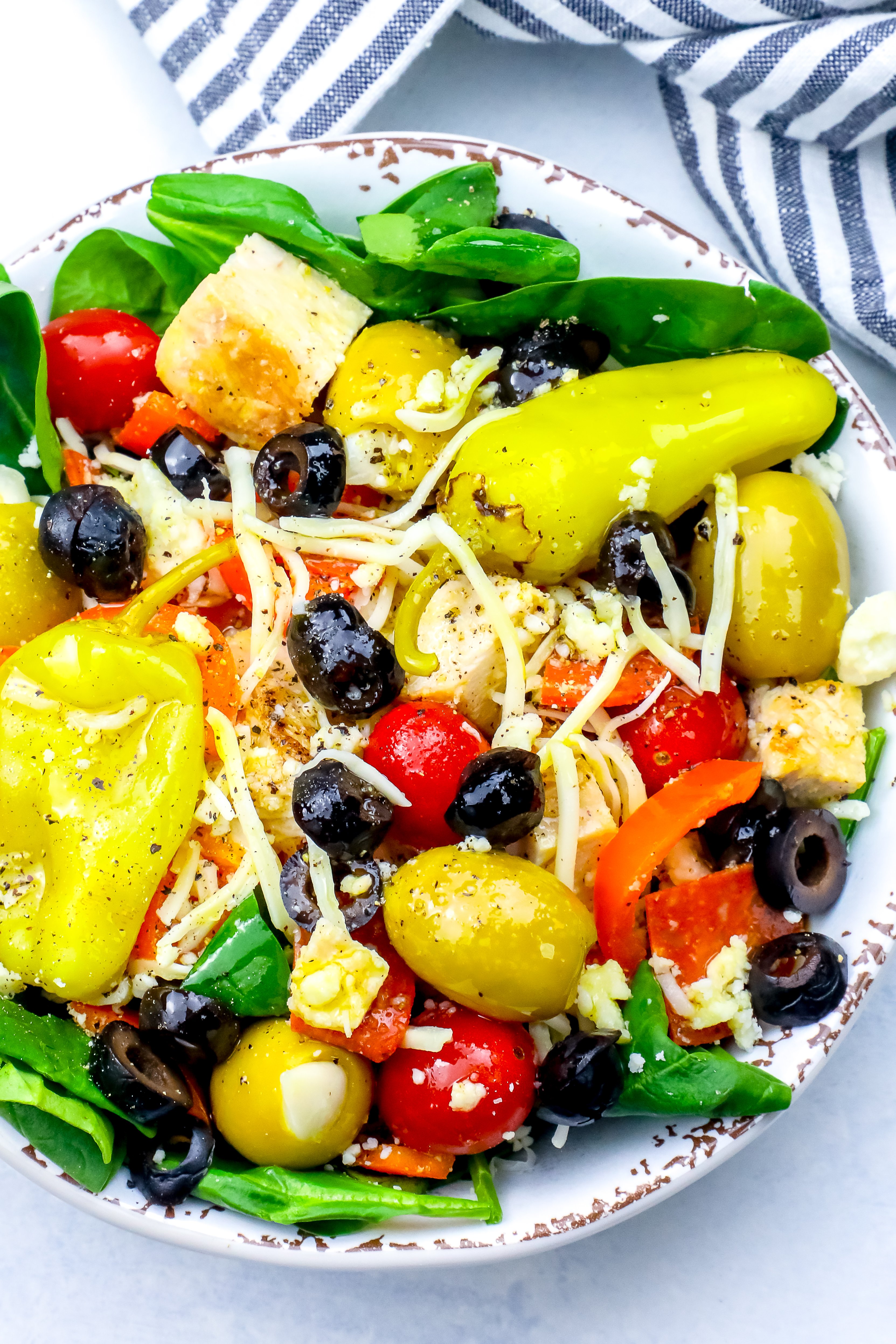 salad with green and black olives, cheese, tomatoes, chicken, and pepperoncini peppers