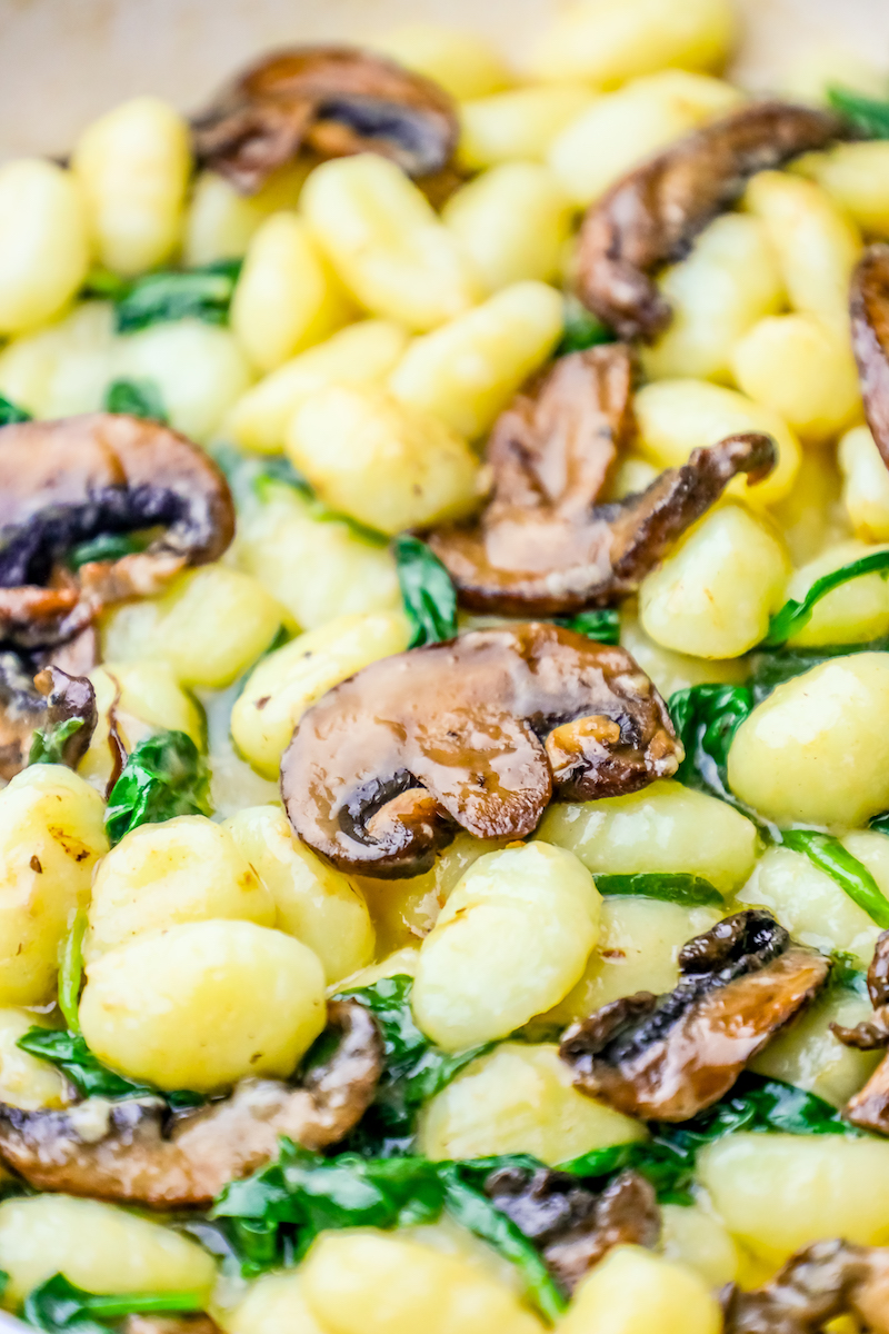 Gnocchi with creamy mushroom and spinach sauce in a skillet.