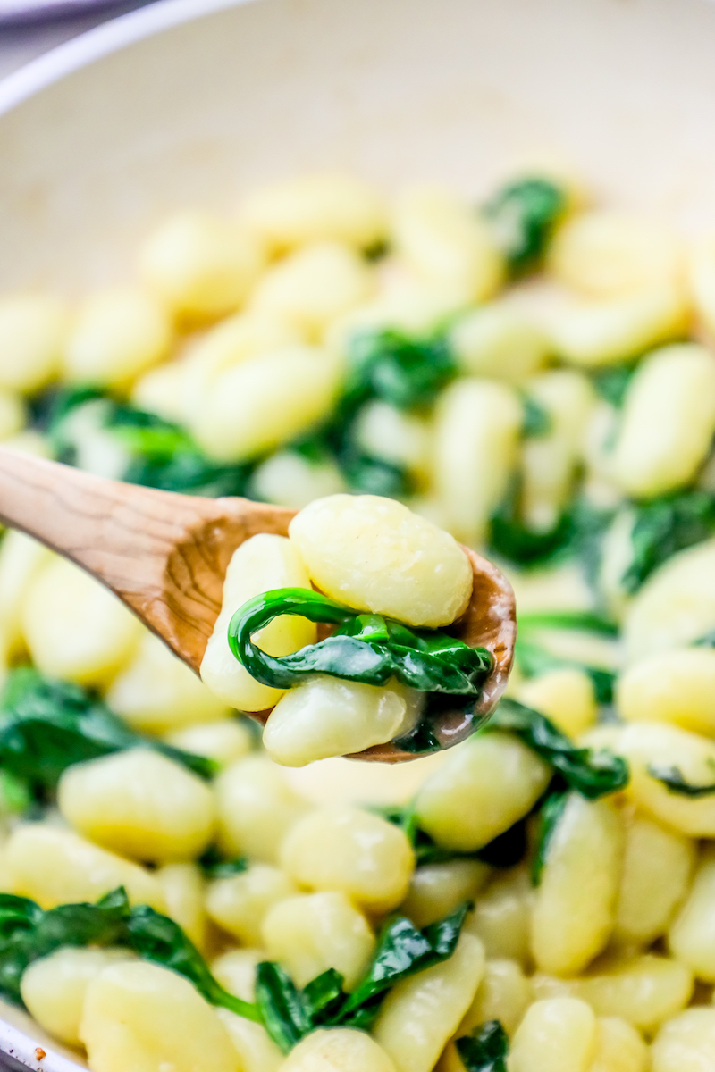 gnocchi with wilted spinach around it and cream sauce