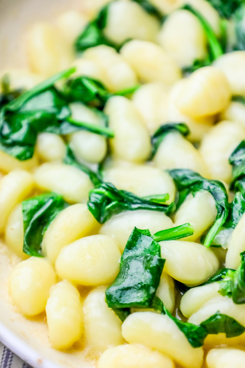 gnocchi with wilted spinach around it and cream sauce