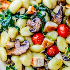 Creamy Tuscan Chicken Gnocchi Recipe with mushrooms and spinach in a white bowl.