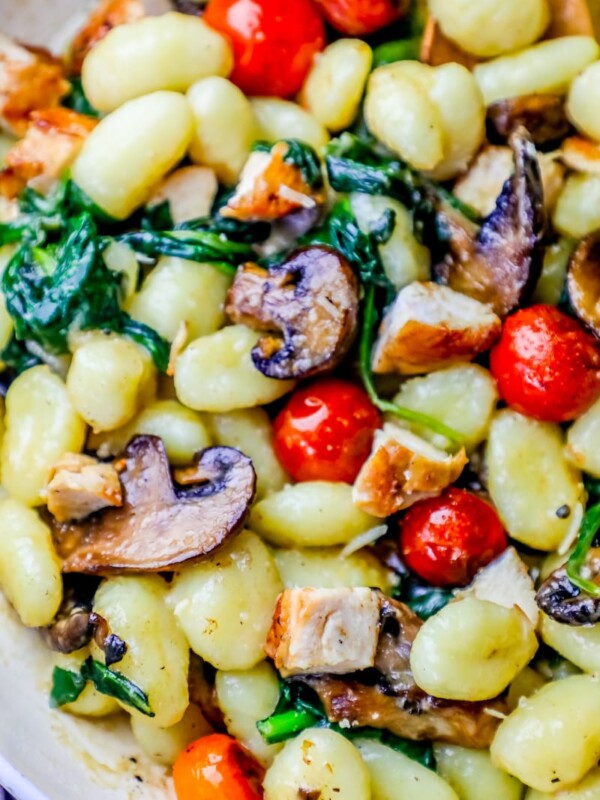Creamy Tuscan Chicken Gnocchi Recipe with mushrooms and spinach in a white bowl.