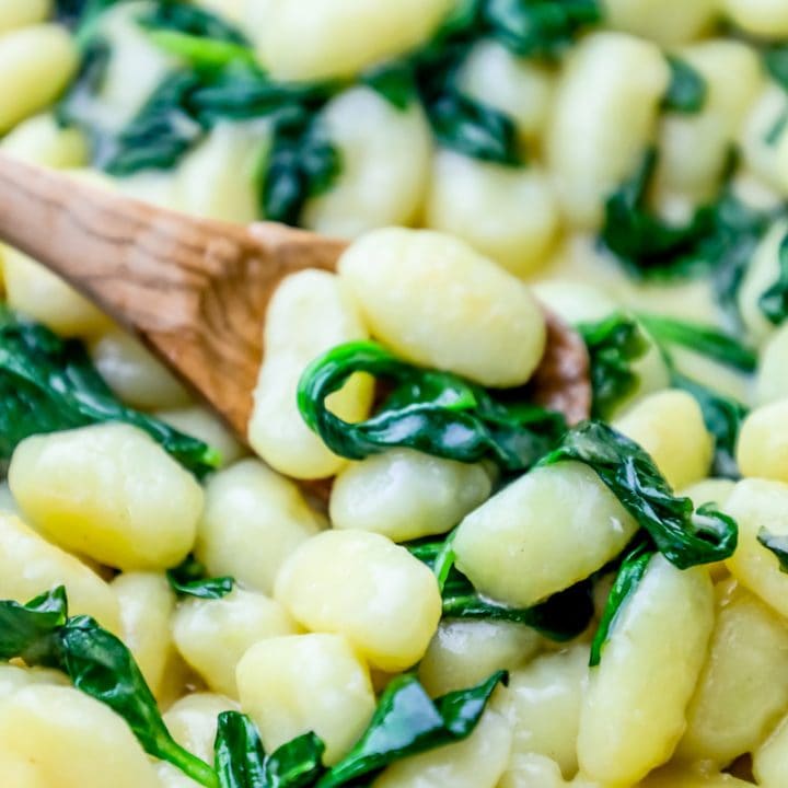 Cook store-bought gnocchi with parmesan and spinach, using a wooden spoon.