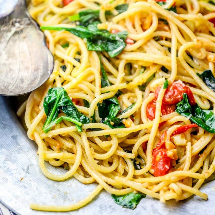 A plate of spaghetti with spinach and tomatoes cooked in a one pot tuscan spaghetti style.