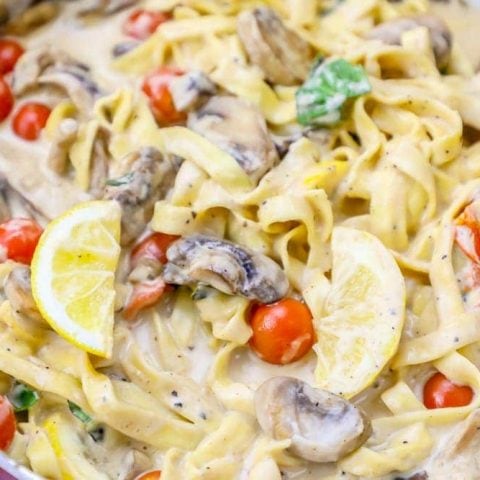 Creamy fettuccine with mushrooms and tomatoes in a pan.