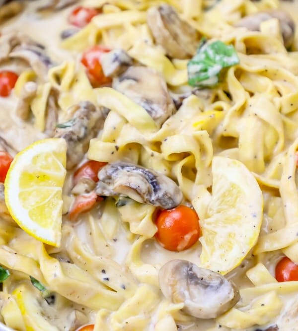 Creamy fettuccine with mushrooms and tomatoes in a pan.