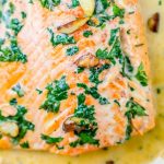 whiskey cream sauce salmon topped with chopped parsley and garlic cloves on top