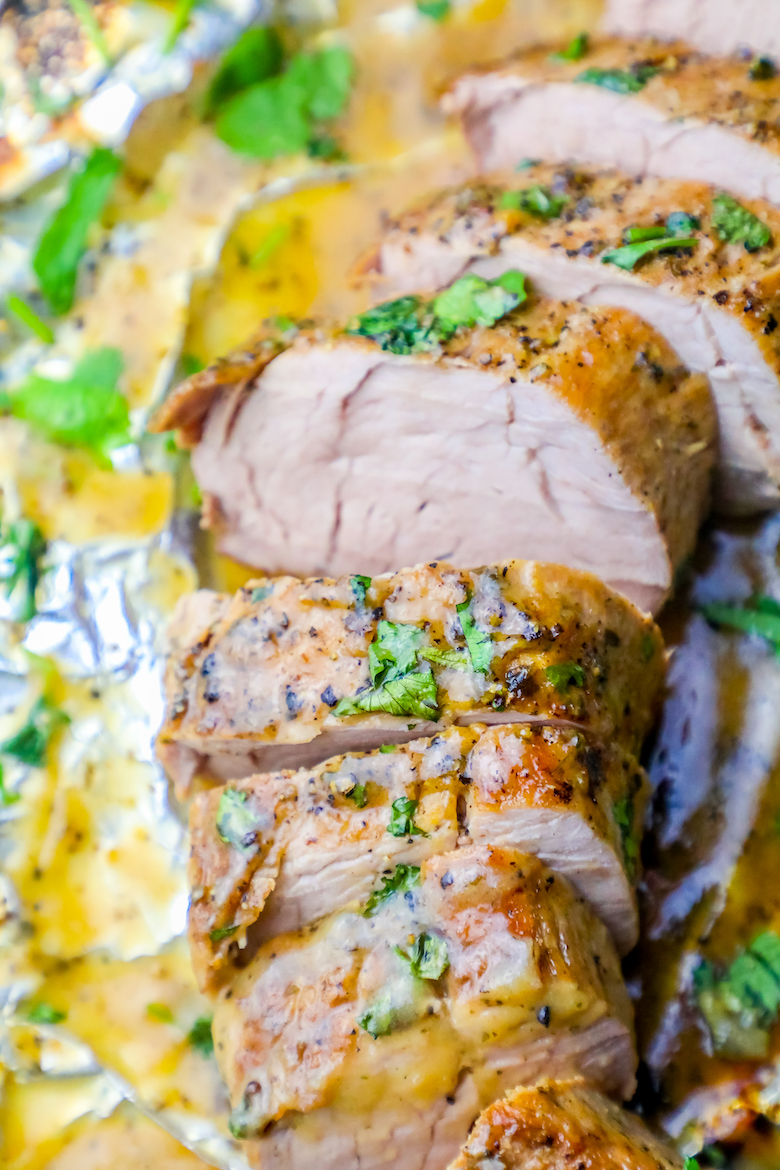 picture of pork tenderloin with cilantro on it and butter in tin foil up close.