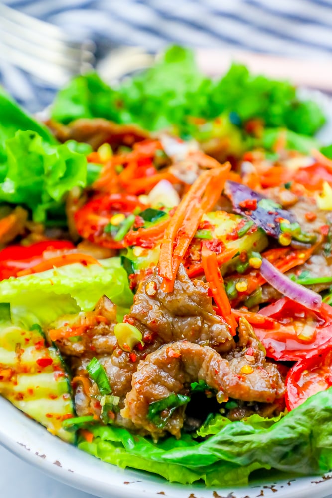 lettuce on a plate with beef, carrots, tomatoes, and kimchi dressing.