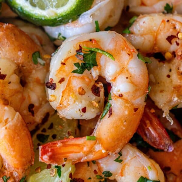 Close-up of Cilantro Lime Sautéed Shrimp garnished with chopped herbs, red pepper flakes, and lime wedges—perfect for those wanting to learn how to cook shrimp with a fresh, zesty twist.