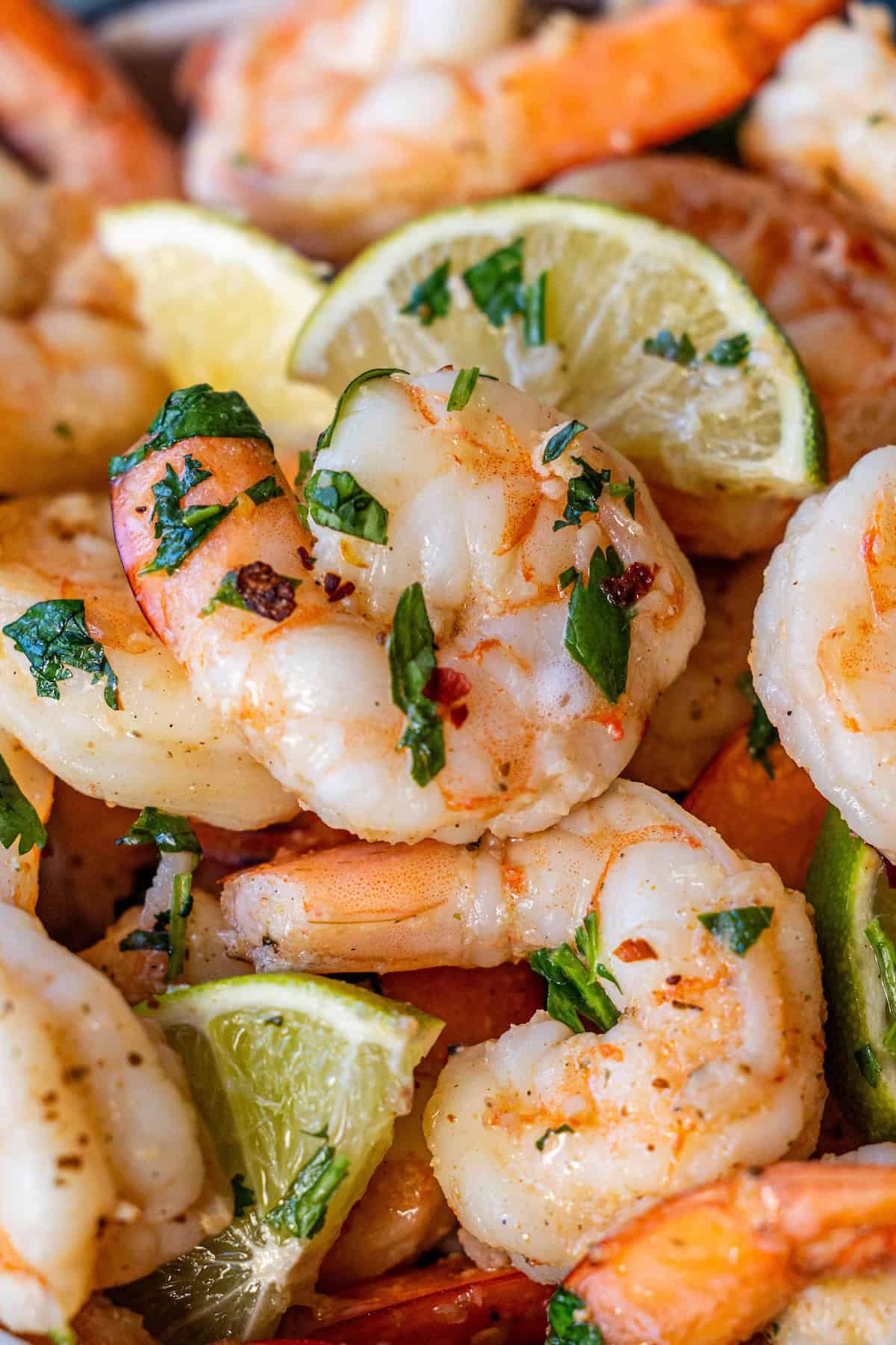 Close-up of Easy Cilantro Lime Shrimp garnished with chopped parsley and red pepper flakes, served with fresh lime wedges.