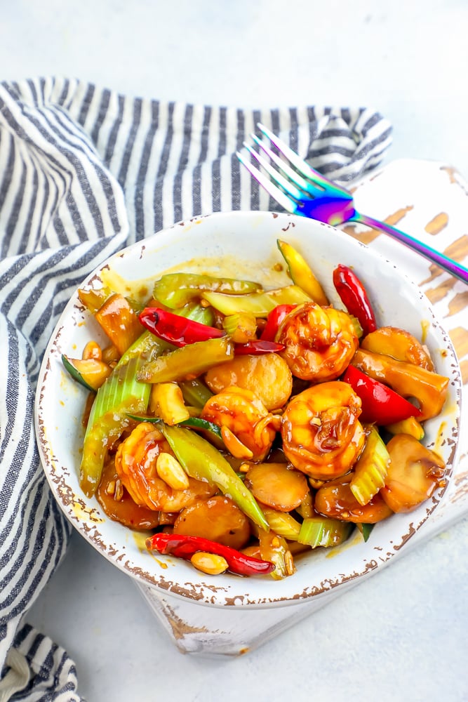 kung pao shrimp in a white bowl with striped towel and fork picture