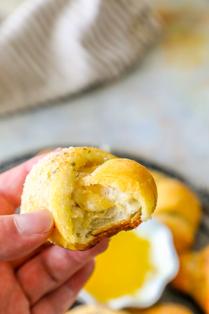 a garlic knot being dipped into melted butter