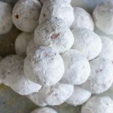 A pile of white powdered sugar donut holes on a table.