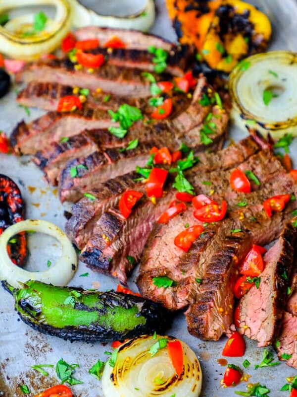 Grilled steak with peppers and onions on a baking sheet prepared using a carne asada recipe.