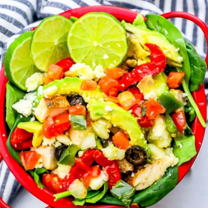 A red bowl filled with chicken, vegetables, and lime wedges, perfect for a keto chicken taco salad.