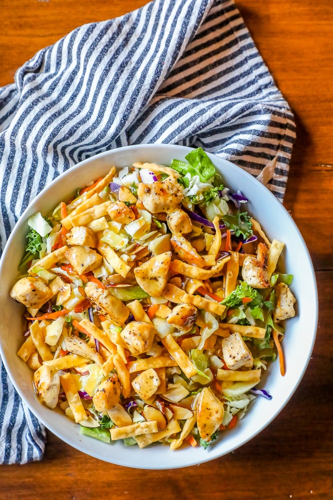 delicious chicken Asian salad in a white bowl with a striped towel in the background