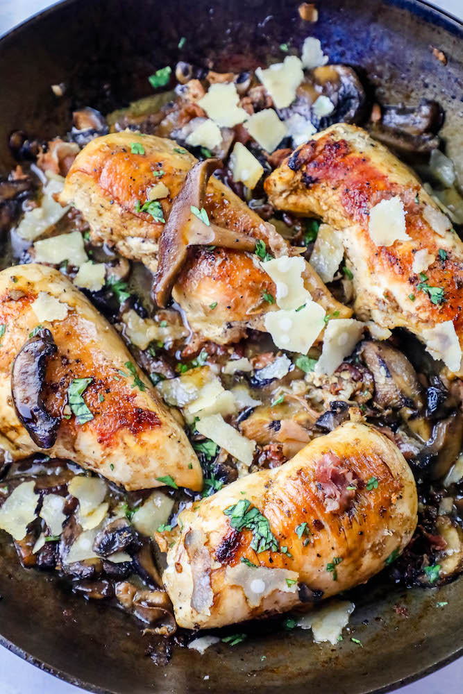 pan with chicken breasts, mushrooms, and parmesan cheese in it