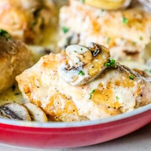 Creamy garlic chicken breasts with mushrooms in a red skillet.