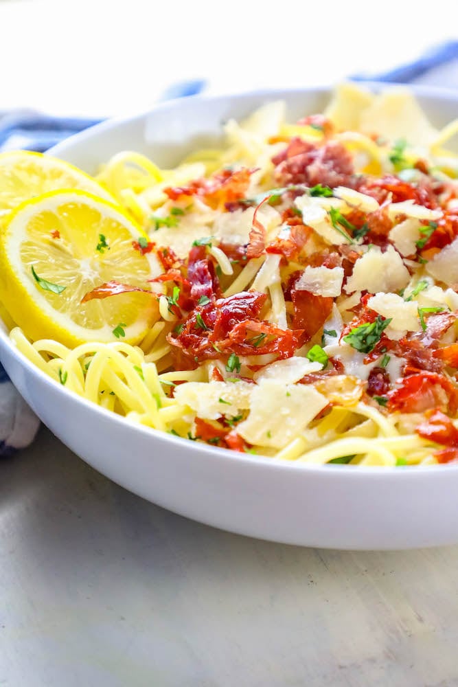 A bowl of linguine with bacon and parmesan in a creamy lemon sauce.