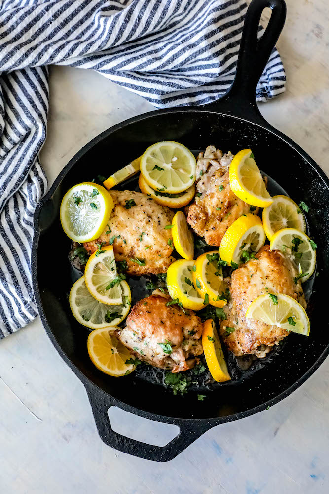 chicken thighs in a cast iron skillet with sliced lemons