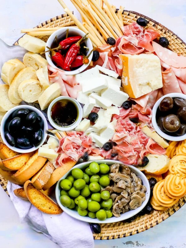 An Ultimate Italian Cheese Plate featuring a variety of cheeses and meats served in a wicker basket.