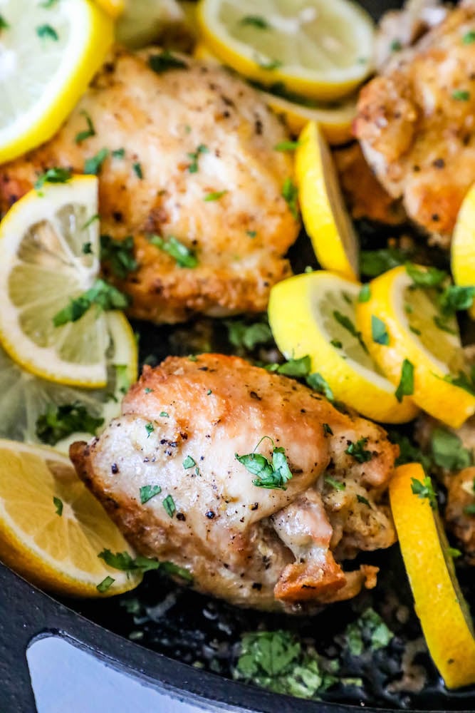 chicken thighs in a pan with sliced lemons and cilantro 