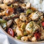 A close-up of a bowl filled with cooked chicken pieces, bell peppers, tomatoes, and herbs—this Keto Italian Chicken Skillet Dinner is served with a portion of white rice visible in the background.