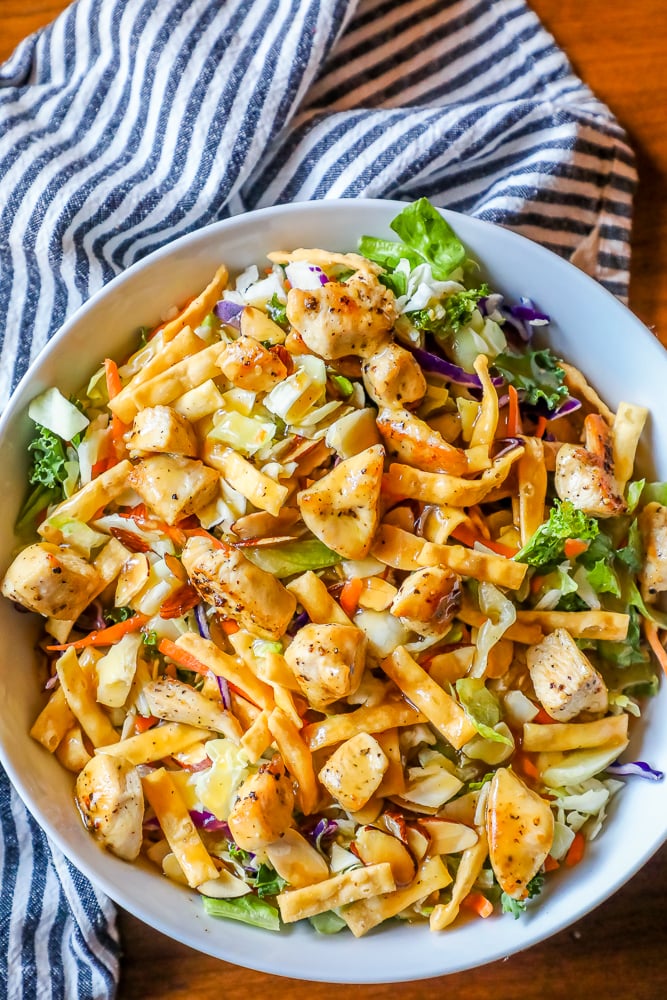 chicken Asian salad in a white bowl with a striped towel in the background