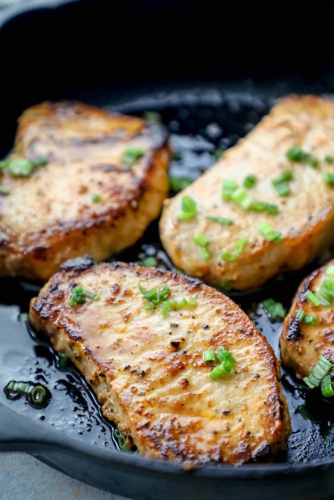 baked pork chop in a cast iron pan with chives on top