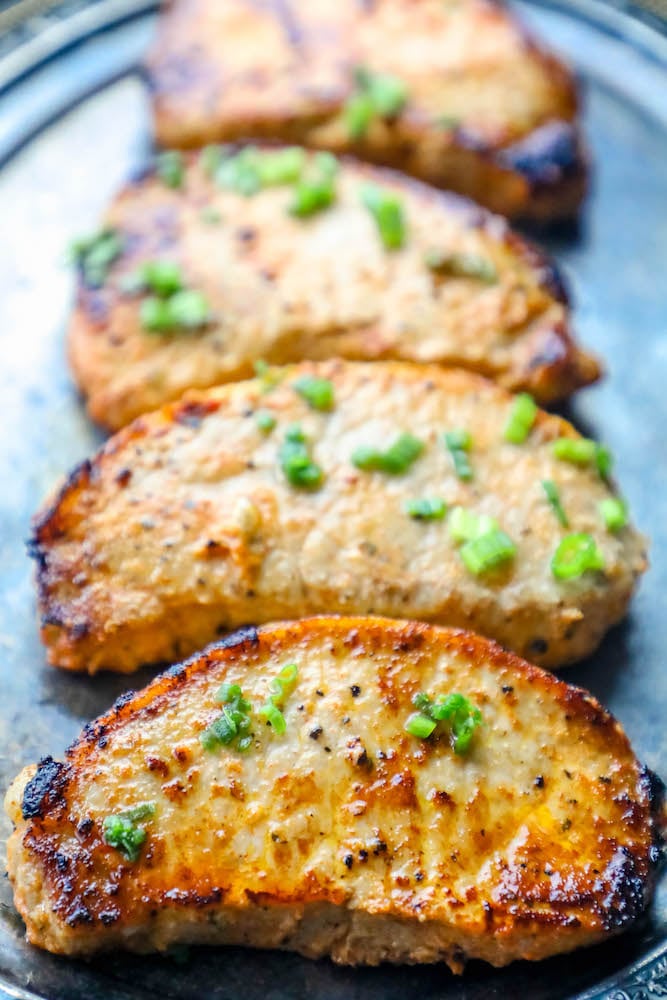 Picture of baked pork chops on a tray with chives on top