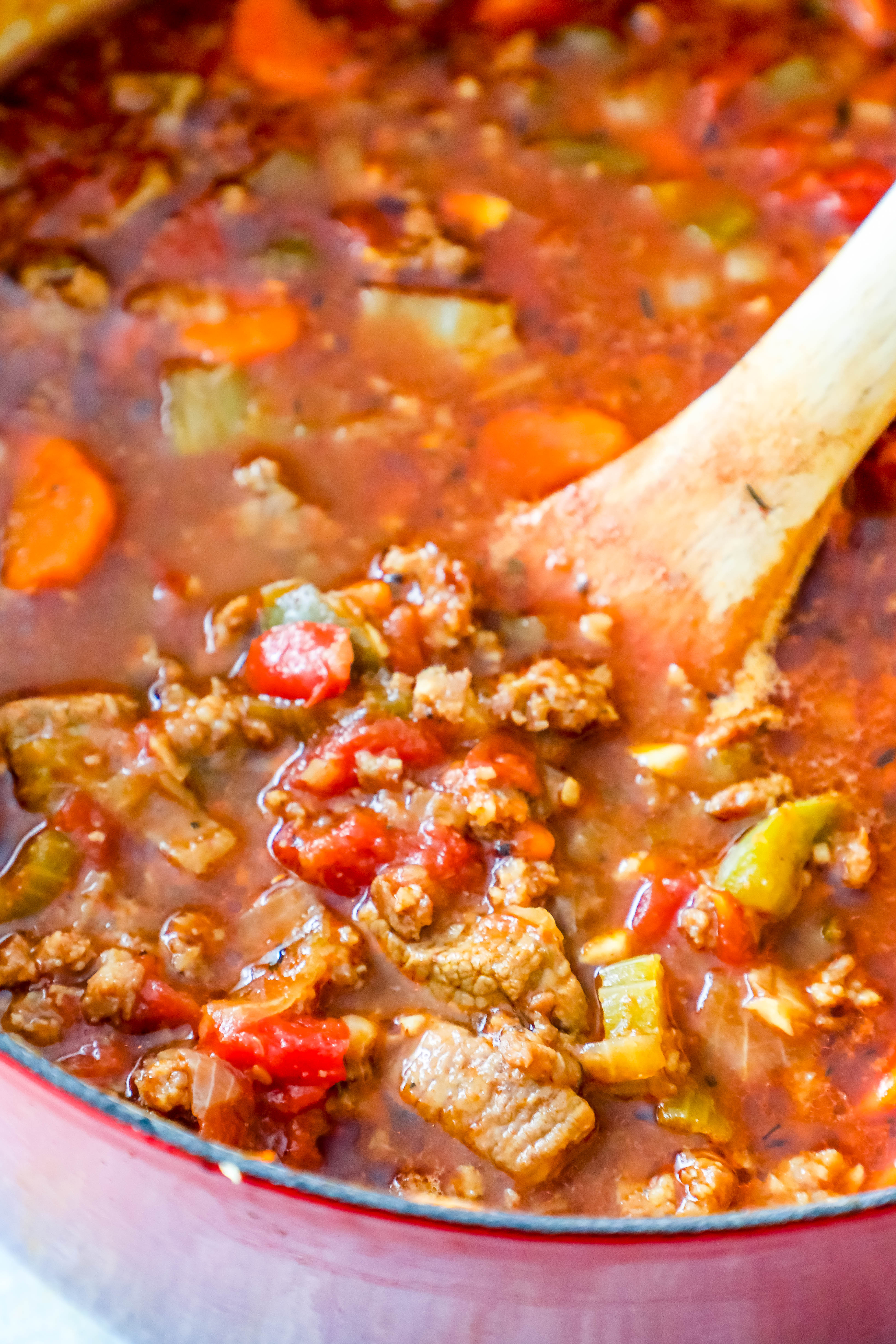 wooden spoon in a red pot full of steak and ground beef keto chili 