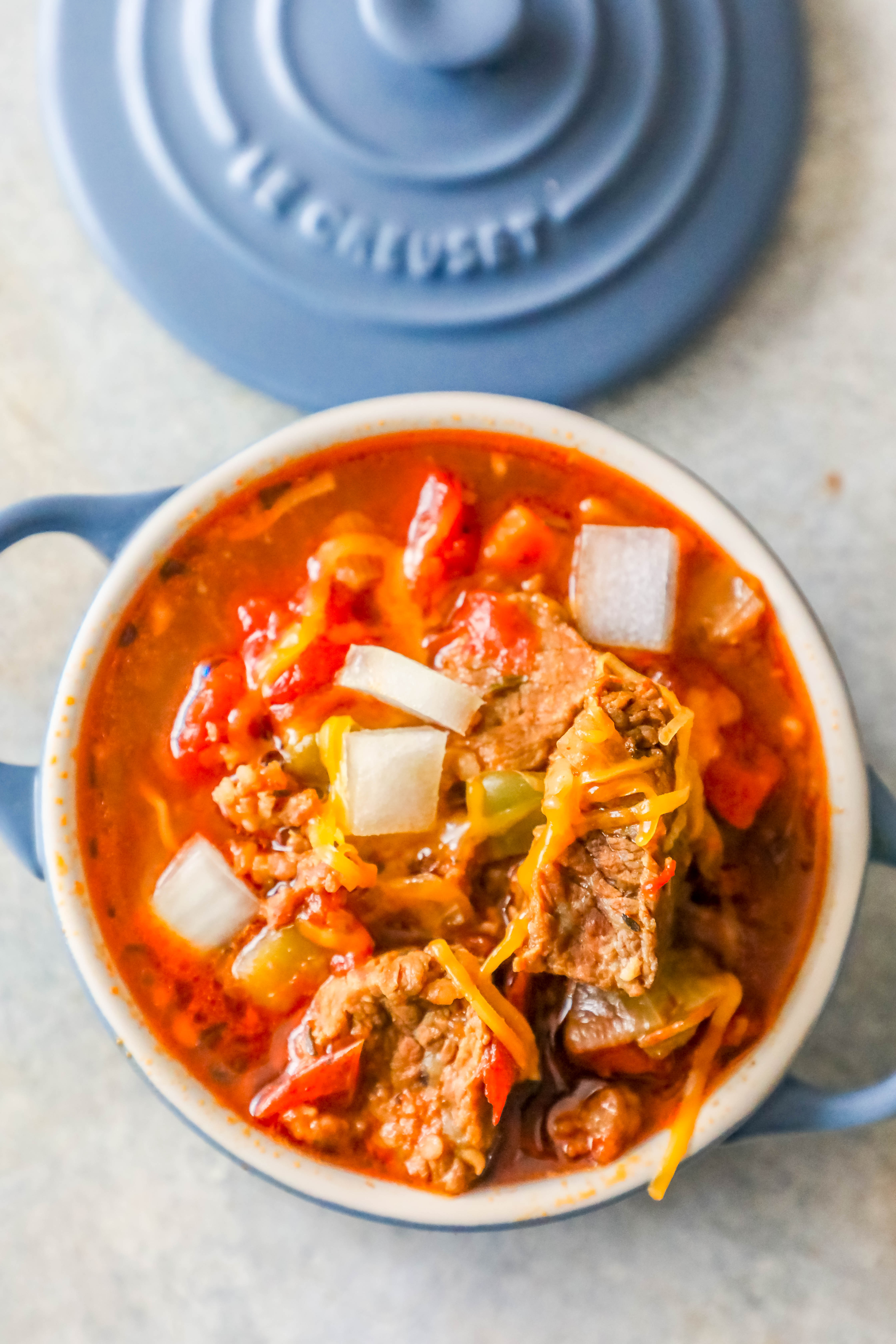 steak chunk chili in a blue bowl with handles