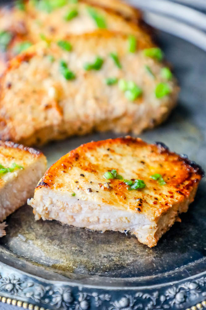 baked pork chop cut in half on plate with chives on top