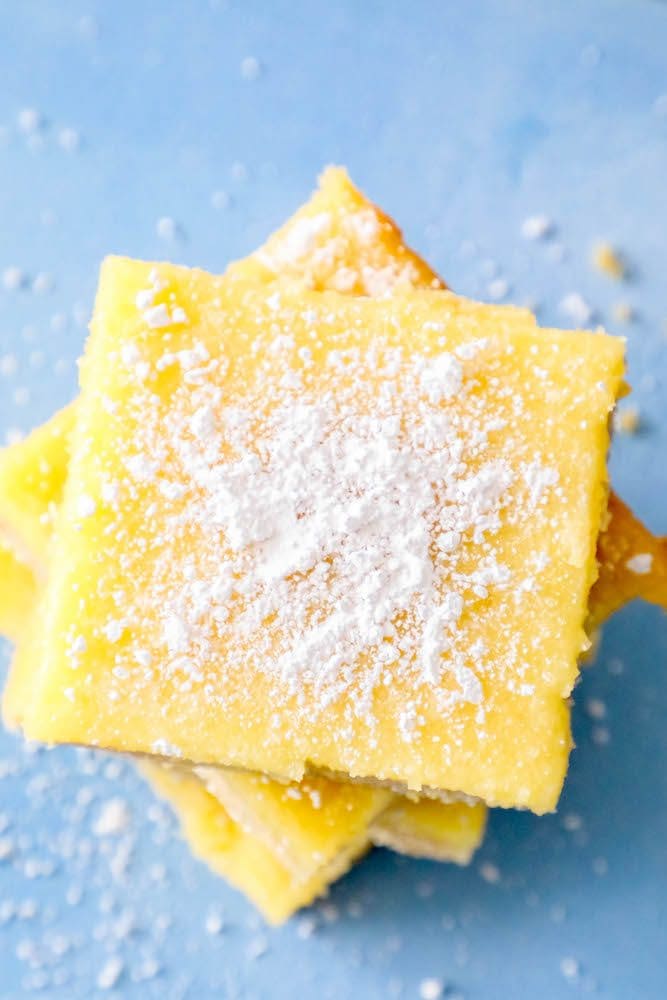 picture of lemon bars stacked on top of each other with powdered sugar sprinkled on top 