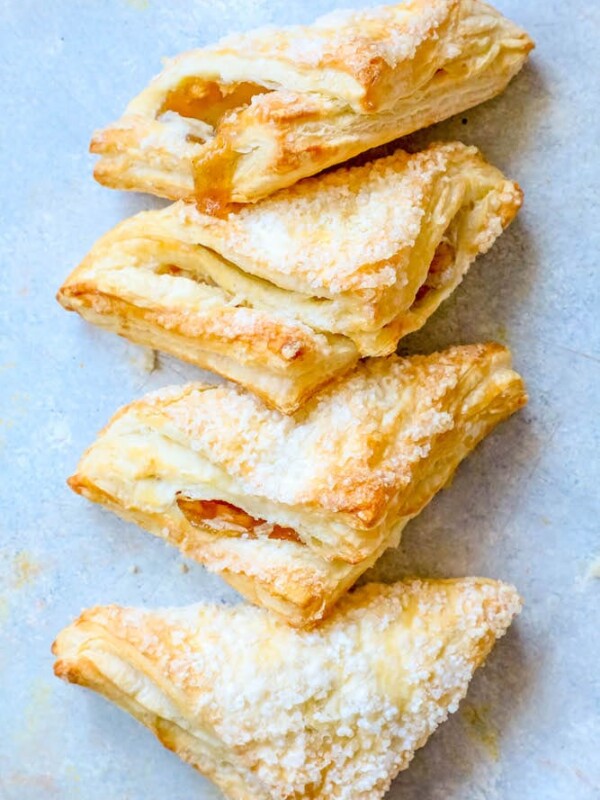 A stack of easy apple turnovers with powdered sugar on a blue background.