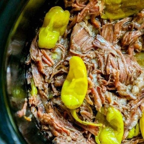 A slow cooker full of beef and peppers prepared with an easy Mississippi Roast recipe.
