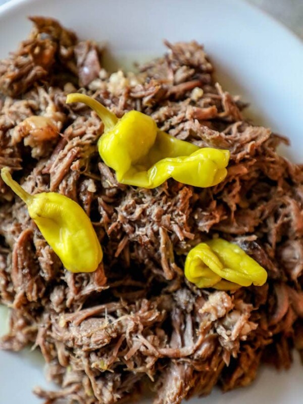 A plate of delicious pulled pork with peppers on it, prepared using the Best Slow Cooker Mississippi Roast Recipe.