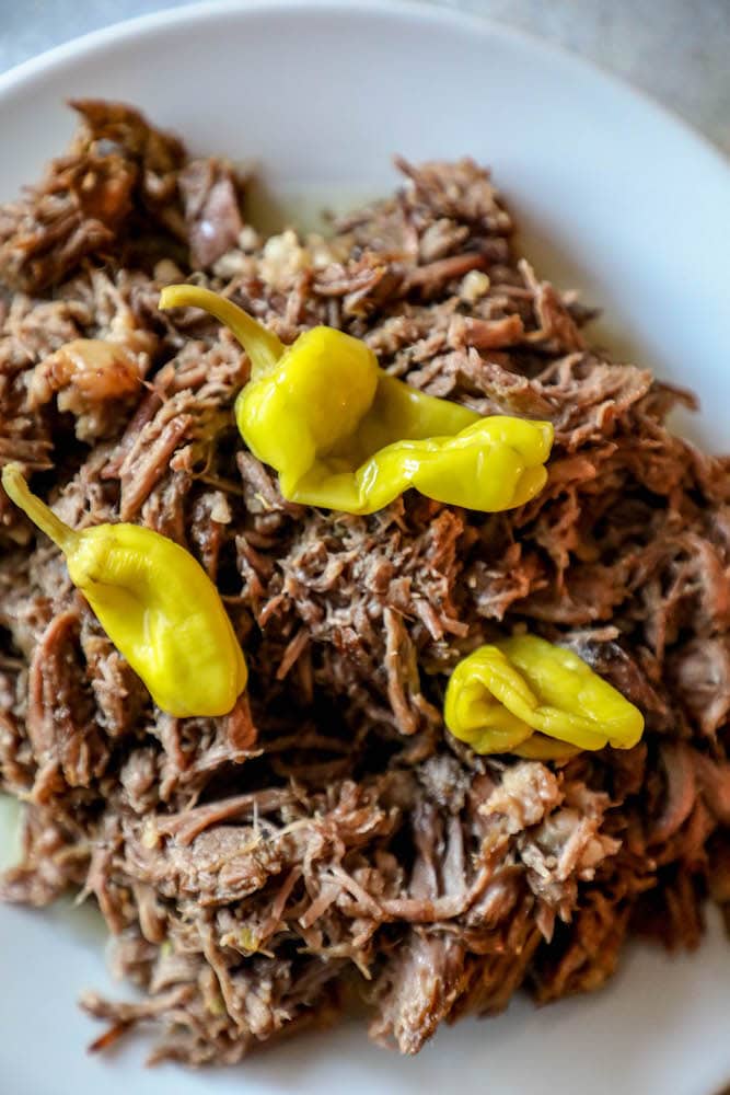 picture of pepperoncinis sitting on top of shredded pot roast 