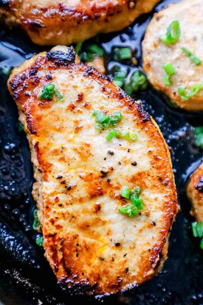 baked pork chop in a cast iron pan with chives on top