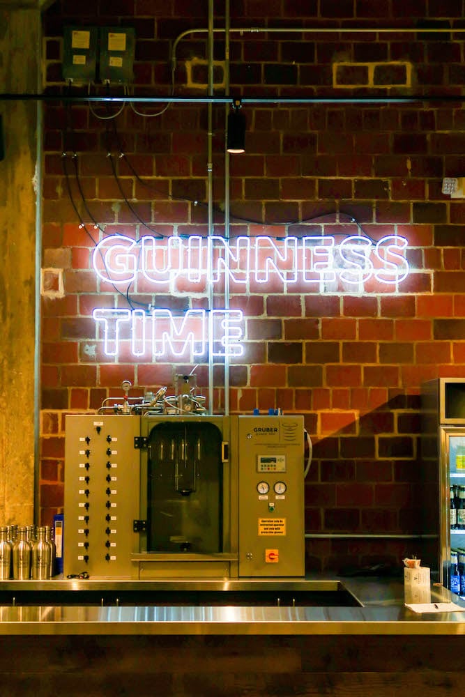 picture of neon light that says guinness time in a brewery